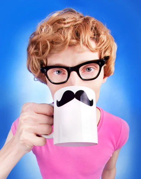 Nerd chico sostiene una taza con bigotes falsos — Foto de Stock