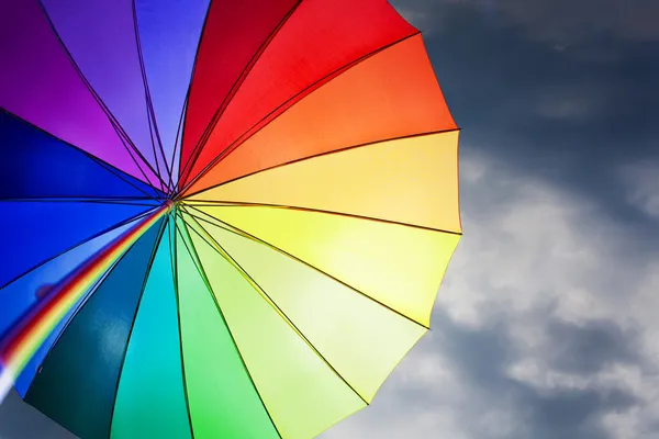 Радужный зонтик на фоне впечатляющего неба — стоковое фото