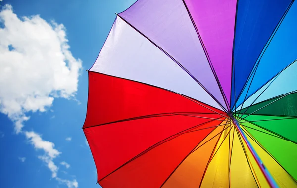 Paraguas arco iris sobre fondo de cielo azul — Stockfoto