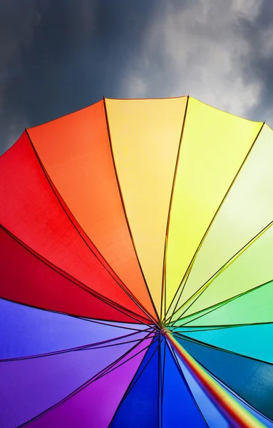 Regenboog paraplu op dramatische hemelachtergrond — Stockfoto