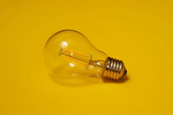 Przezroczysta żarówka LED na żółtym tle — Zdjęcie stockowe