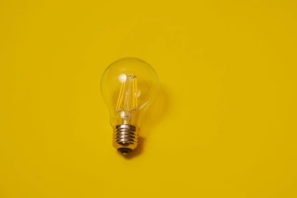 Przezroczysta żarówka LED na żółtym tle — Zdjęcie stockowe