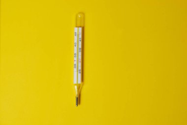 Sarı arka planda civa termometresi izole edildi. Düz bir manzara. Boşluğu kopyala