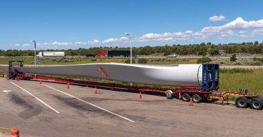 Single long wind turbine blade on a truck resting at a rest area in Idaho state.