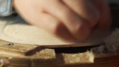 Luthier, atölyedeki bankta çiğ ahşap keman tabağı ve parmak uçağıyla çalışıyor.
