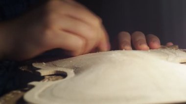 Luthier, atölyedeki bankta çiğ ahşap keman tabağı ve parmak uçağıyla çalışıyor.