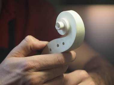 Luthier 'in elinde keman kafası tasarımı ve oyması var.