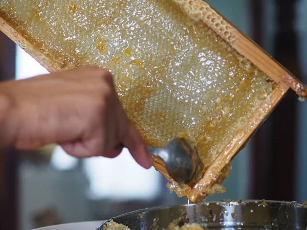 Natural raw honey being filtered ad dripped through a strainer to filter our bees wax.