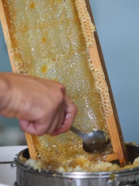 Natural raw honey being filtered ad dripped through a strainer to filter our bees wax.