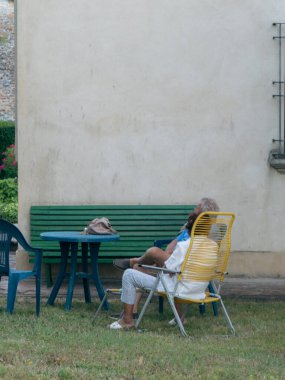 Neşeli yaşlı karı koca çimenlerde dinleniyor.
