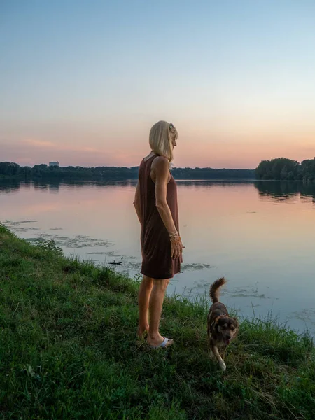 Güzel bir kadın gün batımında nehrin kenarında tatilin tadını çıkarır.