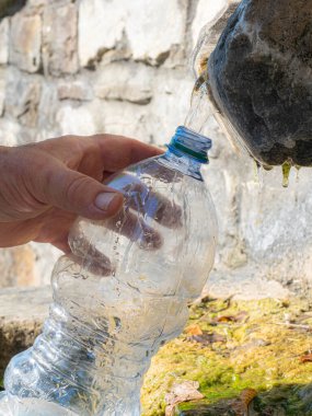 İtalya 'da güneş ışığı ve doğal arka planda şişeye dökülen kaynak suyunu iç.