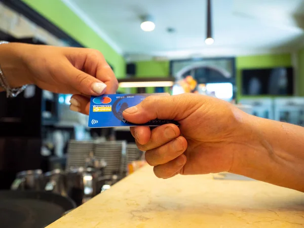 它们的顺序与在一家咖啡馆的信用卡支付的客户 酒保拿着信用卡读卡器机和后付款返回到女性客户的借记卡 — 图库照片
