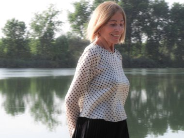 single female pensioner having fun in a park - aging free and wellness concept