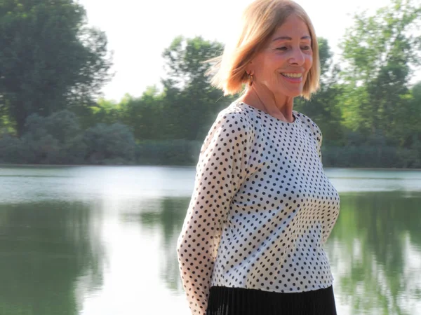 single female pensioner having fun in a park - aging free and wellness concept