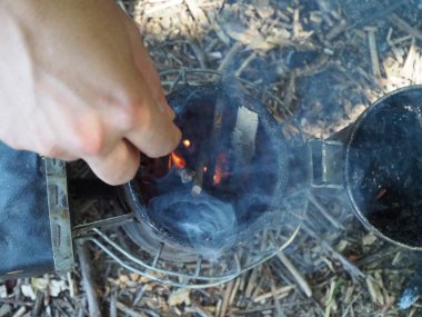 starting a bee smoker before harvesting honey hives in the farm.