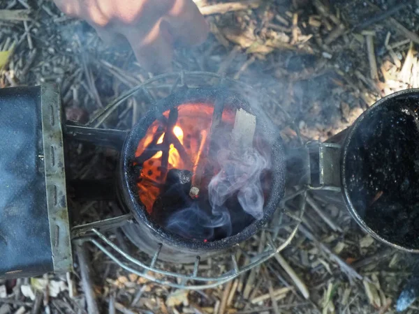 starting a bee smoker before harvesting honey hives in the farm.