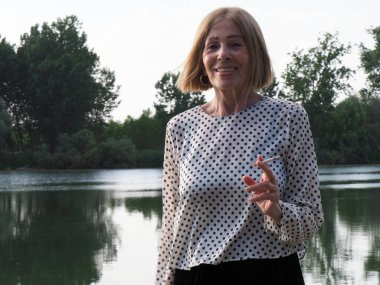 Kadın emekli parkta eğleniyor ve sigara içiyor - yaşlanma ve sağIık kavramı