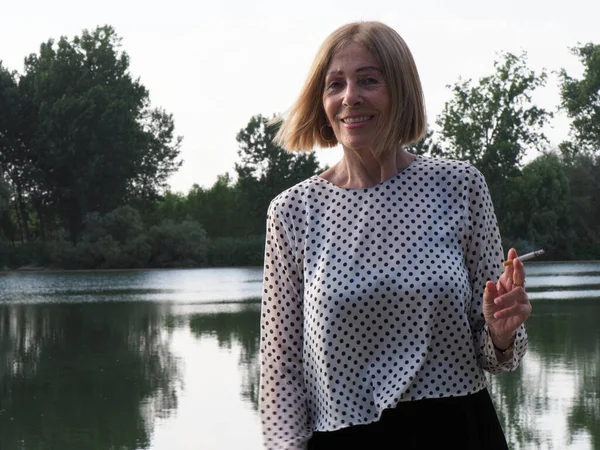 Kadın emekli parkta eğleniyor ve sigara içiyor - yaşlanma ve sağIık kavramı