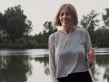 Kadın emekli parkta eğleniyor ve sigara içiyor - yaşlanma ve sağIık kavramı