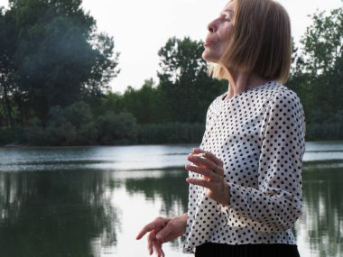 Kadın emekli parkta eğleniyor ve sigara içiyor - yaşlanma ve sağIık kavramı