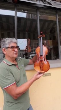 Luthier, İtalya, Cremona 'daki atölyesinin önünde yaptığı son kemanı gösteriyor.