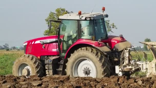 田舎の土地を耕す赤いトラクターの4Kビデオ — ストック動画