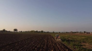 4k video görüntüsü traktör insansız hava aracı ile kırsal alanda karayı sürüyor.