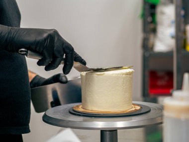 Profesyonel fırıncı çikolatalı ve kremalı pastayı tuzlu karamel ile süslüyor.