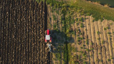 Hava manzaralı traktör dronu kırsal alanda toprağı sürüyor..