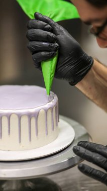 Şef kremalı pasta süslemek için çanta kullanıyor.