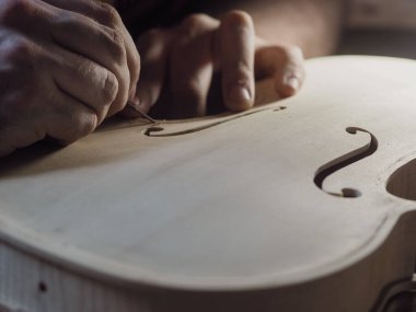 Profesyonel usta zanaatkar Luthier 'in bir atölyedeki ahşap kemanla ilgili ayrıntılı çalışmalarını yakından takip edin..