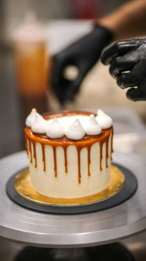 Şef kremalı pastanın üstünü dekore ediyor.