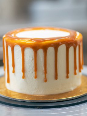 Profesyonel fırıncı çikolatalı ve kremalı pastayı tuzlu karamel ile süslüyor.