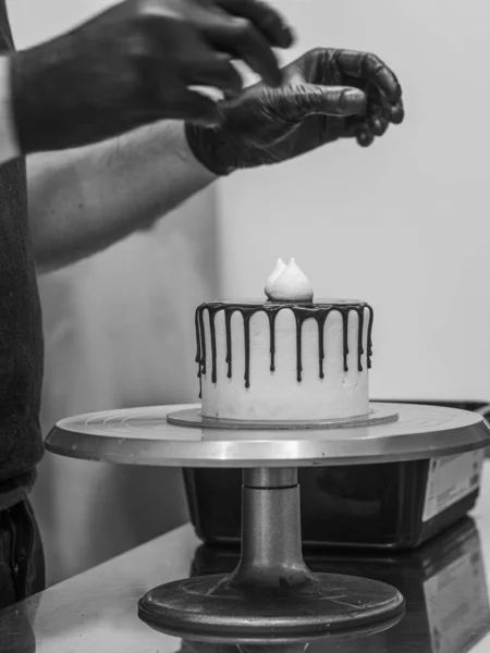 unrecognizable worker preparing a sweet dripping choco cake and berries