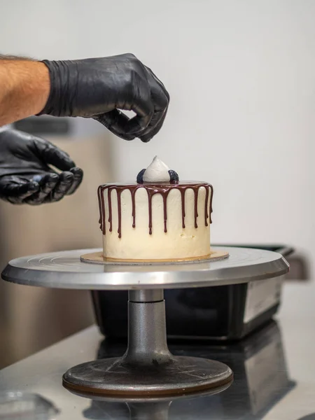 stock image unrecognizable worker preparing a sweet dripping choco cake and berries