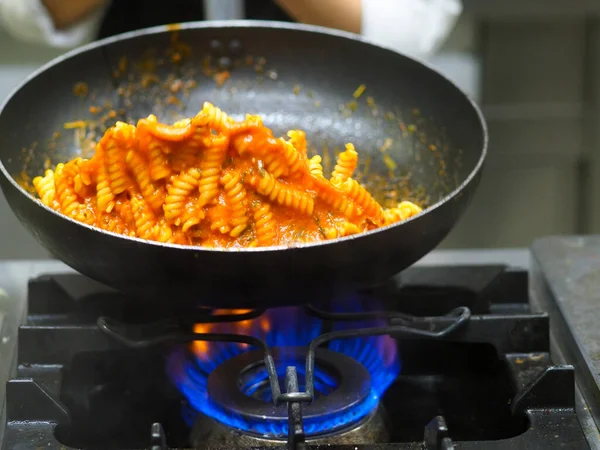 female cook tossing egg pasta in the pan