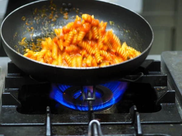 female cook tossing egg pasta in the pan