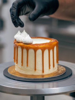 Profesyonel fırıncı çikolatalı ve kremalı pastayı tuzlu karamel ile süslüyor.