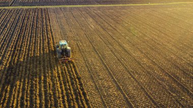 Taşrada araziyi düzleştiren traktörlü çiftçi.
