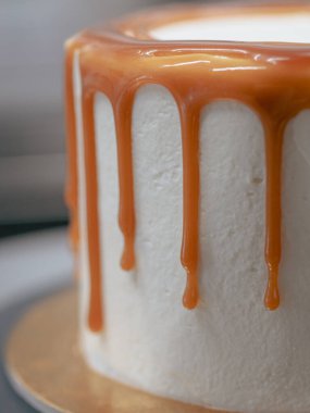 Profesyonel fırıncı çikolatalı ve kremalı pastayı tuzlu karamel ile süslüyor.