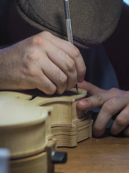 Close up of professional master artisan luthier painstaking detailed work on wood violin in a workshop.