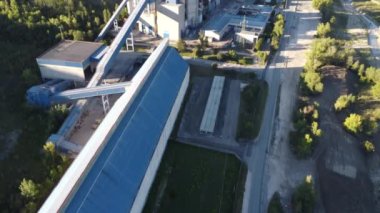Mavi bulutlu arka planda depoları olan çimento üretim tesisinin havadan görüntüsü. Stok görüntüleri. Endüstriyel bölge ve çimento üretim fabrikasının üzerinde uçuyor.