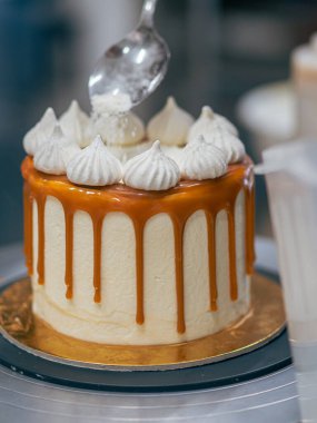 Profesyonel fırıncı çikolatalı ve kremalı pastayı tuzlu karamel ile süslüyor.