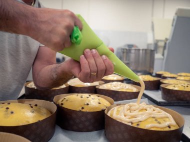 Bir grup keki süslemek için dondurulmuş dolgu poşeti kullanan bir zanaatkar.