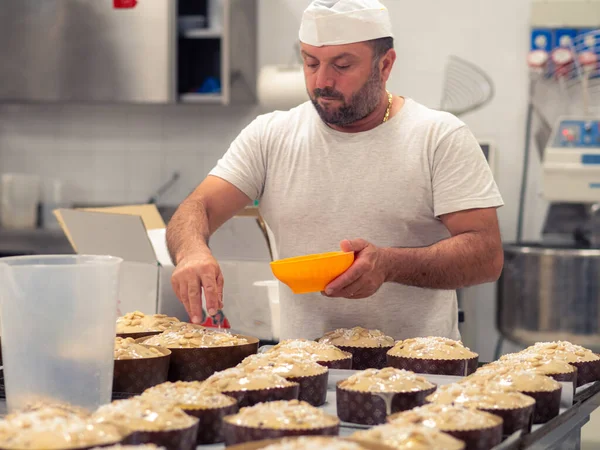 chef topping panettone italian cake with almonds