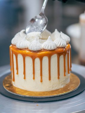 Profesyonel fırıncı çikolatalı ve kremalı pastayı tuzlu karamel ile süslüyor.