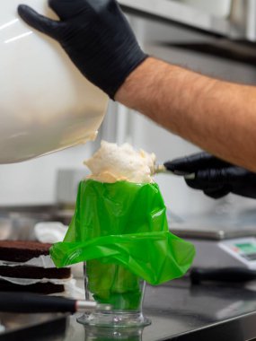 Şef, profesyonel mutfak laboratuarında ganache süsleme keki kullanıyor.