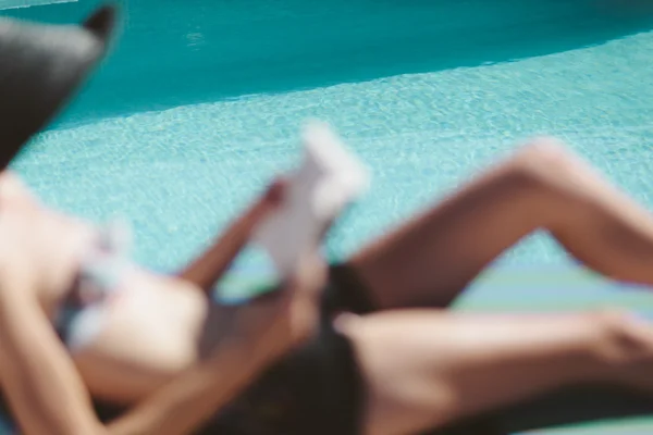 Donna rilassante a bordo piscina lettura — Foto Stock