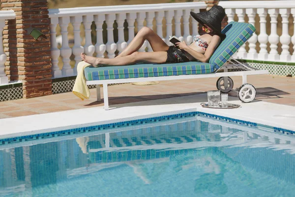 Jeune fille lisant près de la piscine — Photo